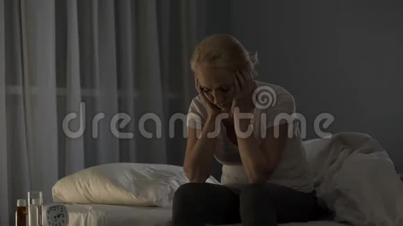女士坐在床上由于严重的偏头痛和剧痛无法入睡视频的预览图