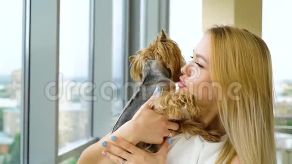 金发美女抱着一只毛茸茸的小狗亲吻她的肖像视频的预览图