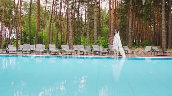 戴着长面纱的新娘在游泳池里走来走去豪华酒店的婚礼视频的预览图