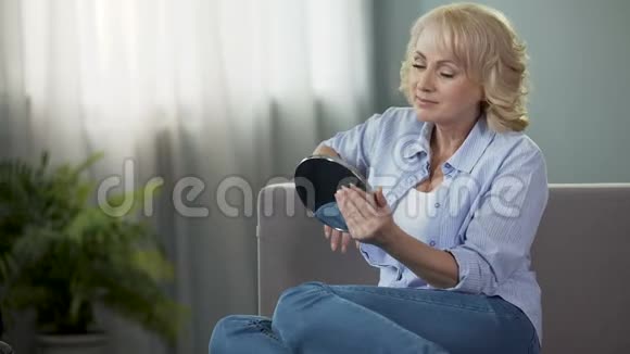 成熟的女人看着手镜享受着倒影防老化妆品视频的预览图
