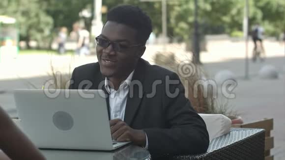 一位非洲男子在咖啡馆里用笔记本电脑向他的非洲女同事解释商业战略视频的预览图