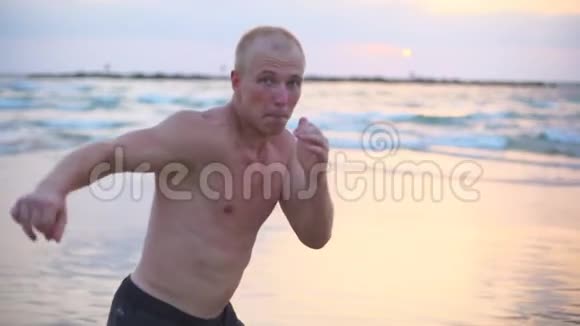 年轻的肌肉男在海边练习拳击男运动员在附近独自练习自卫视频的预览图