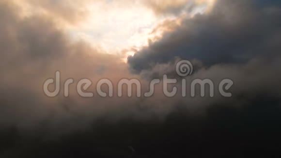 在云层上方的夕阳下用照相机穿过傍晚的雨云在云层中飞行得很棒空中景观视频的预览图