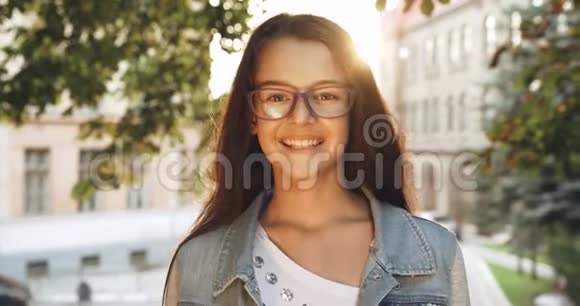 幼儿画像戴着紫色眼镜的小女孩正对着太阳照明弹的镜头微笑4K录像视频的预览图