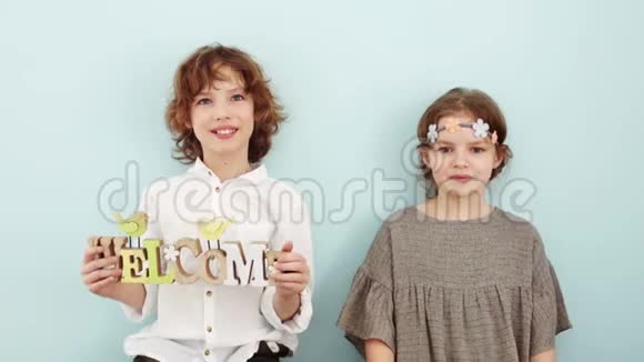 工作室里的春拍男孩和女孩拿着春天装饰的标志孩子们笑女孩拿着一个标志视频的预览图