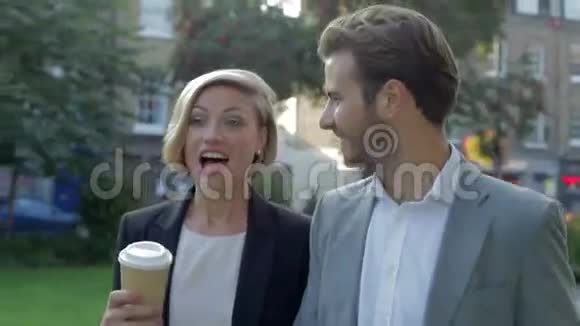 商务情侣步行穿过公园带外卖咖啡视频的预览图