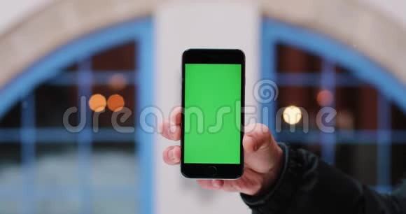 雪落在一个男人身上他手里拿着智能手机手里拿着绿色的屏幕视频的预览图