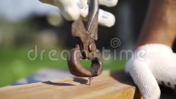 戴着工作手套的人在户外用生锈的拔钉器从木头上拔出锤钉后院手工制作DIY材料视频的预览图