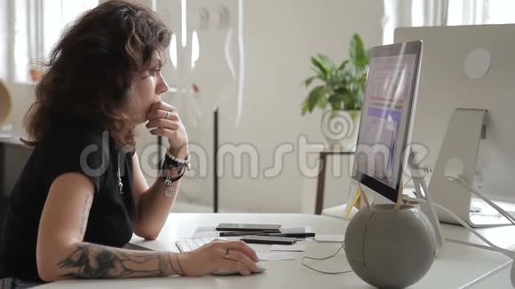 有纹身的非正式女人正在用电脑桌工作视频的预览图