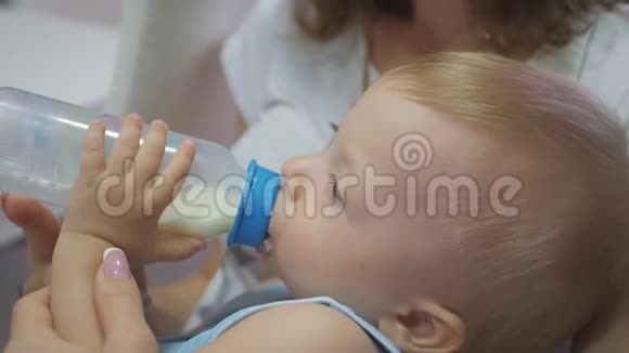 小男孩用瓶子睡着了可爱的小男孩从瓶子里喝牛奶关门视频的预览图
