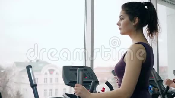 美丽的健身女孩在健身房模拟器上锻炼视频的预览图