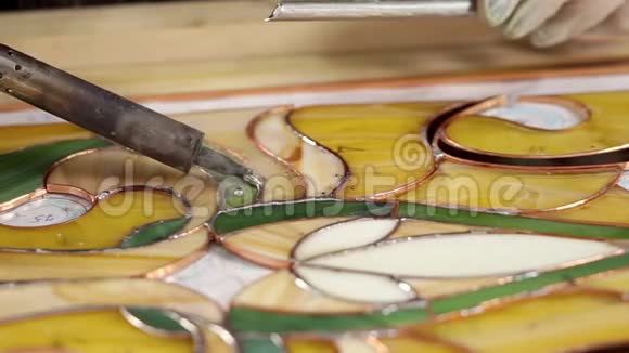 师傅正在用烙铁制作一个彩色玻璃面板用来固定视频的预览图