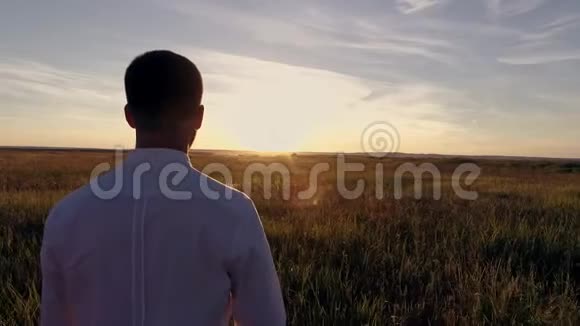 日落时分一个年轻人正走在田野上视频的预览图