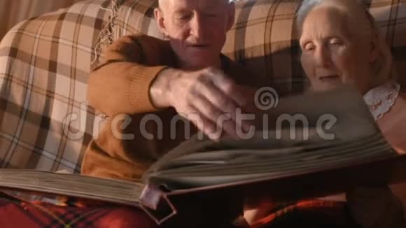 一对老年夫妇正在考虑用格子布包裹的家庭相册视频的预览图