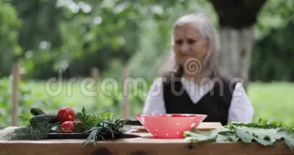 一位白发苍苍的老妇人坐在花园的一张桌子旁视频的预览图