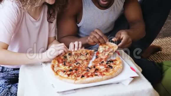 饥饿的多民族夫妇吃披萨男人和女人互相喂食用美味的快餐在用餐期间玩得开心视频的预览图