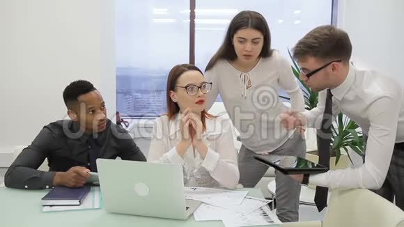 在办公室里一个国际团队正在为一台笔记本电脑集思广益视频的预览图