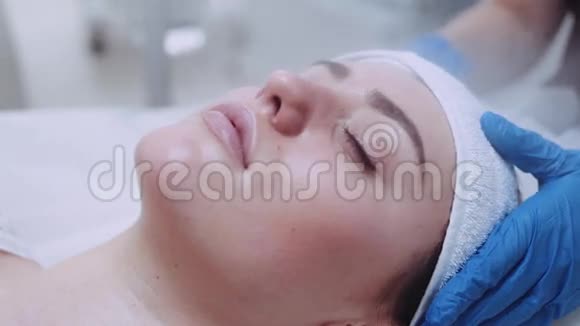 在美丽的水疗中心一位美丽的女性闭着眼睛用蒸汽疗法清洗面部的极端近景视频的预览图