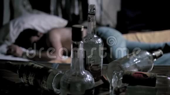 空酒瓶和睡在背景下的男人放在桌上视频的预览图