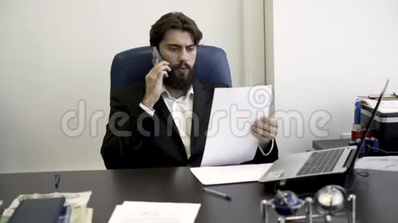 精神集中紧张年轻留胡子的商人打电话坐在办公室里的蓝色皮椅上愤怒视频的预览图