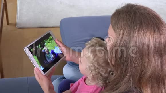 快乐的女孩和妈妈一起看家庭电影视频平板电脑屏幕视频的预览图