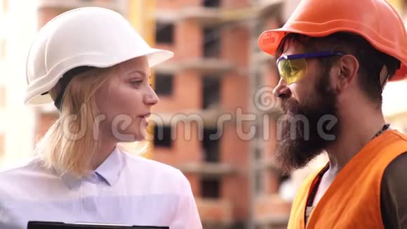 施工工人和工程师在施工现场交谈建筑区戴头盔的工人男性和女性视频的预览图