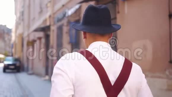 从后面看一个戴着黑帽子的人走在街上视频的预览图
