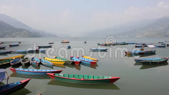 白天在一个山谷的背景下许多空的木制彩色船只在一个光滑的湖上航行视频的预览图