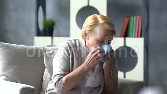 生病的老年妇女咳嗽在杯中服药的背景下抱着头视频的预览图