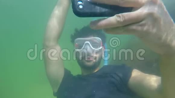 潜水男子慢动作带智能手机在防水箱潜水并在水下拍照视频的预览图