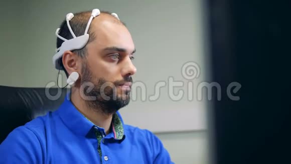 一个戴脑波扫描耳机的人正在操作一台电脑视频的预览图