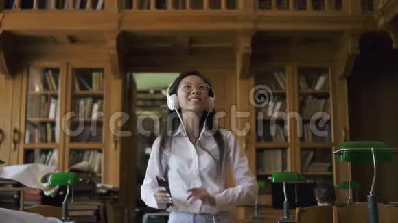 穿着白衬衫戴眼镜听音乐的年轻亚洲女人视频的预览图