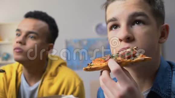 两个男青少年在看电视吃披萨吃便宜的快餐视频的预览图