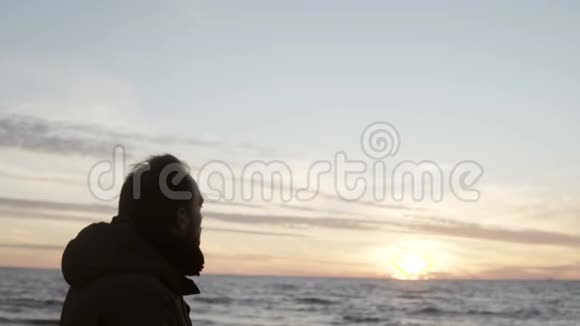 年轻人独自走在海边望着海浪男人在海滩上享受日落视频的预览图