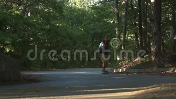一个年轻人学着骑长板它位于森林里穿着格子衬衫和毡帽积极主动视频的预览图