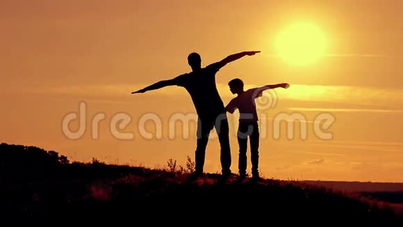 爸爸和儿子在日落时展示飞机的飞行视频的预览图