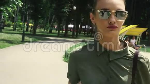 戴着镜子墨镜红唇的性感女人在公园散步视频的预览图