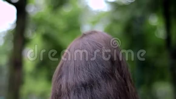年轻的黑发女郎走在街上改善了手部头发的特写视频的预览图