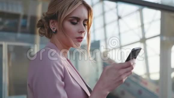 一位优雅的金发商务女士用她的手机旋转在明亮的阳光下环顾四周现代视频的预览图