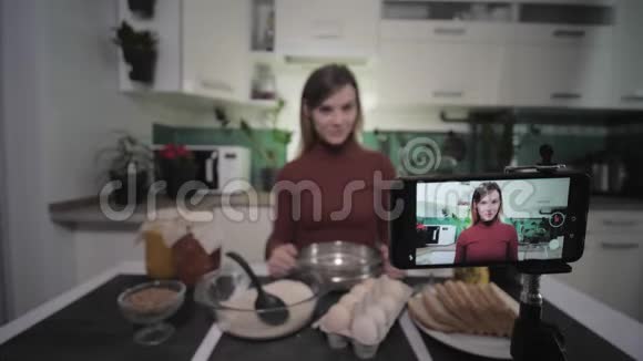 一位家庭主妇的博客厨房里的女时尚博主为她的用户在智能手机上写视频食谱重点是视频的预览图