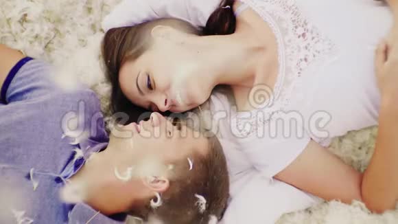 一对相爱的夫妇面对面地躺在羽毛上上下是羽毛和羽毛慢动作视频视频的预览图