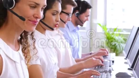 一排呼叫中心的工作人员在办公桌前打字视频的预览图