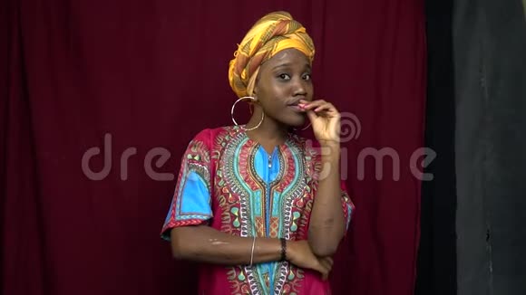 一位穿着非洲传统服装的开朗的黑人妇女双手紧握嘴唇双手伤痕累累视频的预览图