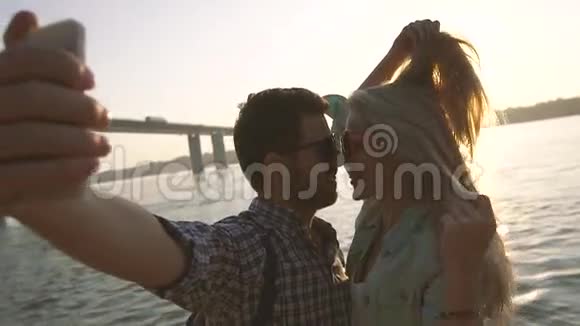 亲吻年轻夫妇在灿烂的阳光和闪闪发光的河流上拍照视频的预览图