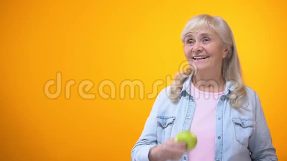 快乐的老年妇女享受新鲜脆苹果的味道口腔护理正畸视频的预览图