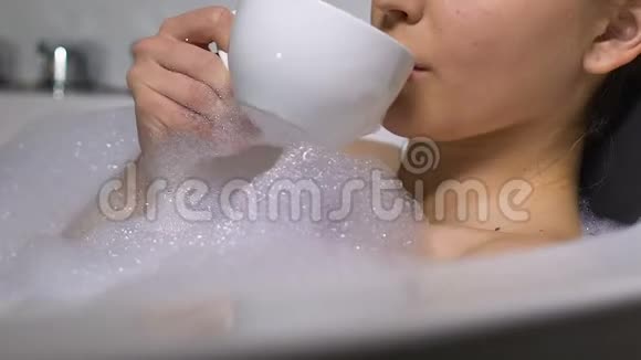 漂亮的年轻女士在浴缸里喝热咖啡享受休闲时光放松身心视频的预览图