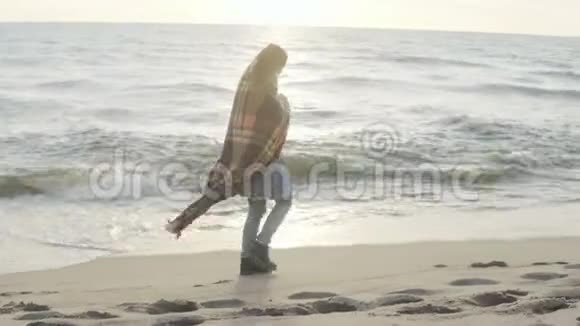 孤独的女人带着格子呢走在沙滩上年轻的女性在寒冷的日子里花时间在海边视频的预览图