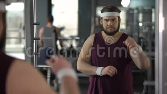 不快乐的超重男人在健身房饮食和运动中看镜子反射视频的预览图