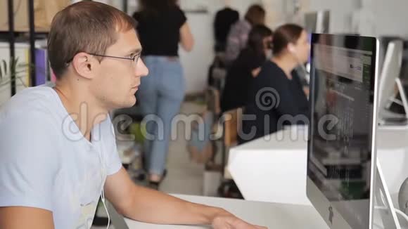 男人在一间嘈杂拥挤的办公室里在电脑前工作视频的预览图