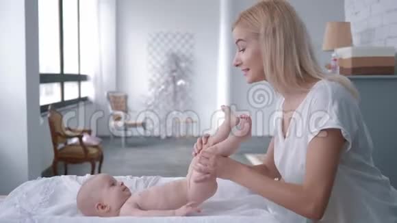 孩子的照顾年轻的母亲在家里的餐桌上给刚出生的女孩换尿布然后把婴儿抱在怀里视频的预览图